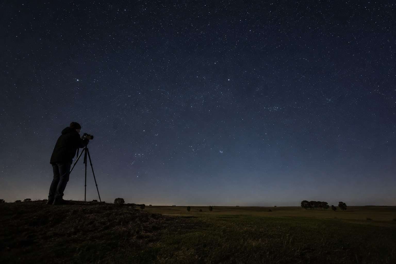 Persona fotografiando un cielo estrellado con cámara y trípode